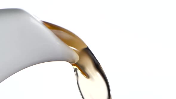 Tea Stream Pouring From White Teapot. White Background, Slow Motion