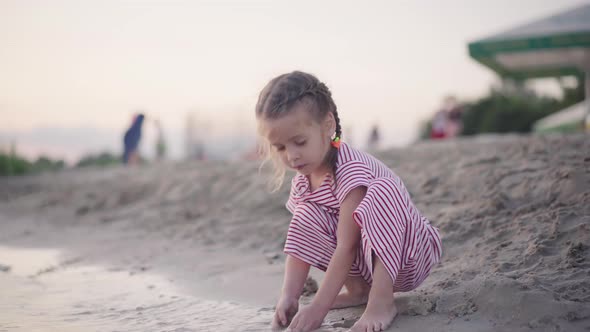 Child Playing Near Water Building Sand Castle On Sea Beach Summer Evening Time