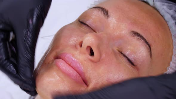 Close-up, Cosmetologist, in Black Medical Gloves, Performs Skincare Procedure, Facial Massage To a