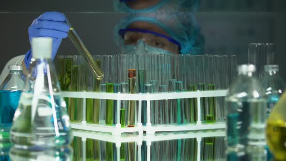 Lab Assistant Comparing Reaction in Tubes With Orange Oily Substance, Science