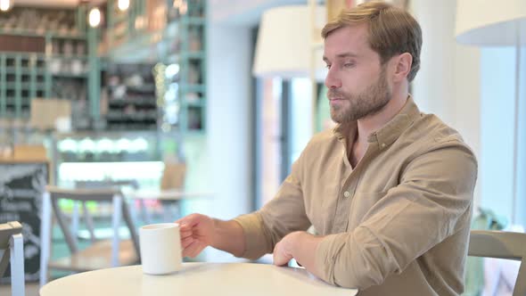 Relaxed Young Man Drinking Coffee in Cafe