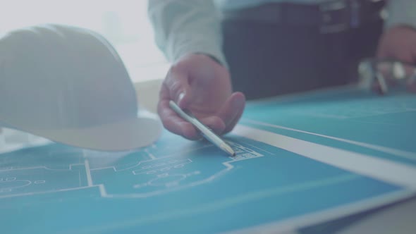 Young engineer-architect in a bright room works with blueprints laid out on a table