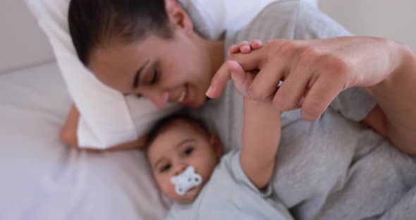 Young loving mother lying with her son on bed at home - Family and motherhood concept