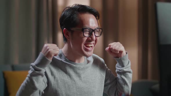 Close Up Of Happy Asian Male Footwear Designer Celebrating While Working On A Desktop Computer