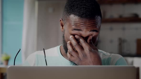 Close Up of Exhausted AfricanAmerican Ethnicity Man Rub Eyes Working on Computer at Home