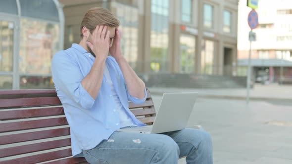 Man with Headache Using Laptop While Sitting Outdoor on Bench