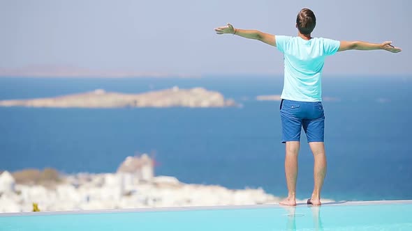 Young Man Relaxing Near Pool with Amazing View on Mykonos, Greece