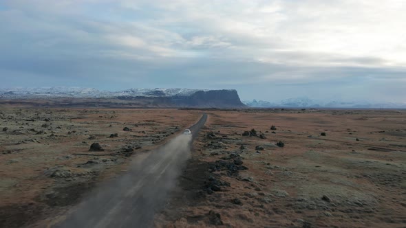 4K drone video of car driving away on a dirt road in Iceland.