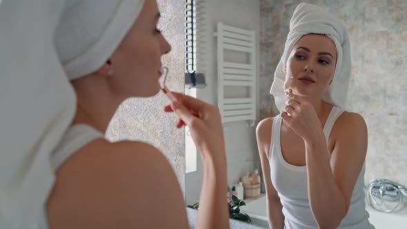 Young caucasian woman using face roller in the bathroom. Shot with RED helium camera in 8K.