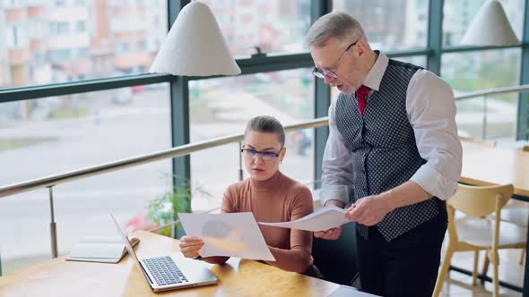 Young woman talks to her boss indoors. 