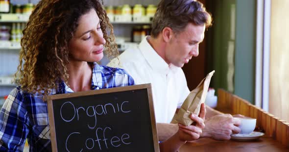 Woman holding a board that reads Organic Coffee