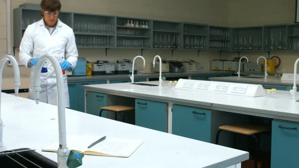 Scientist with sample of red and blue chemical writing his notes