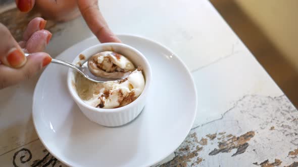 Women Hand with Spoon Eating Ice Cream on Cafe Table