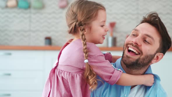 Cute little girl hugging daddy in living room. Young family having fun