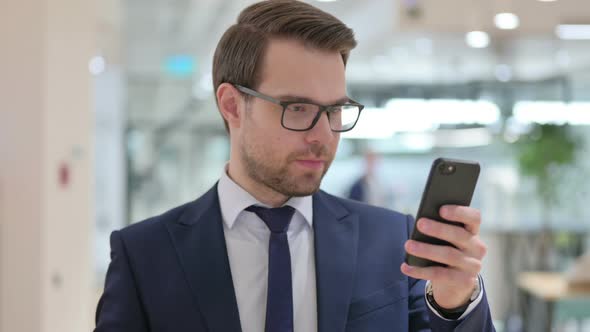 Excited Businessman Celebrating Success on Smartphone 