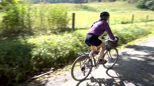 Camera pans with a woman on a mountain bike as she passes the camera and reveals her son riding with