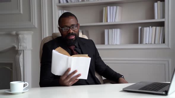 African-American Bearded Man in a Black Suit, Shirt, Stylish Glasses. A Businessman Is Working on a