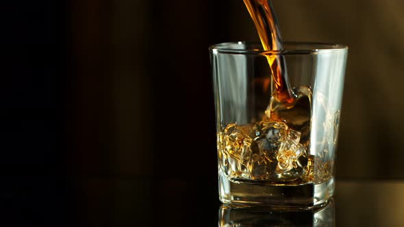 Super Slow Motion Macro Shot of Pouring Whiskey Into Glass with Ice Cubes at 1000Fps alt