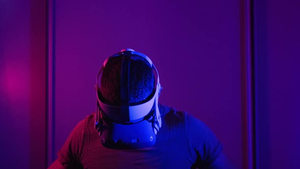 Man in a Virtual Reality Helmet Illuminated in Red and Blue Plays a Game