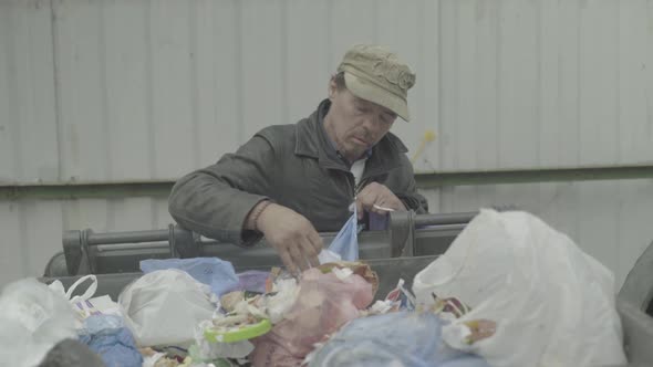 A Beggar Homeless Man Tramp Is Looking for Food in a Trash Can. Kyiv. Ukraine