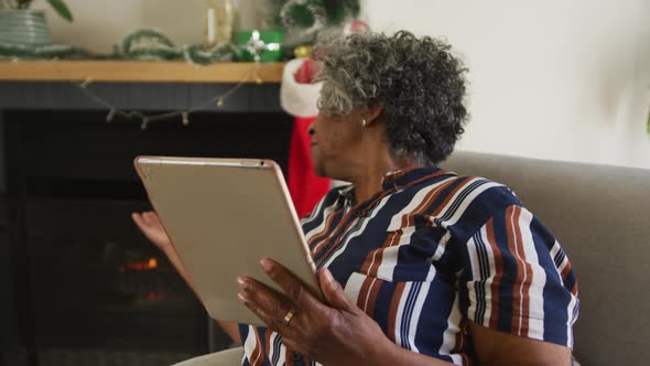 Animation of happy african american senior woman gesturing, having video call at christmas time
