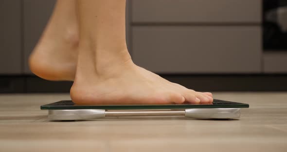 Feet stepping on weighing scales.