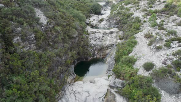 Aerial view of a tiny heart-shaped lake hidden between the rocks of National Park Peneda-Gerês