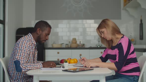 Diverse Couple Managing Family Budget in Kitchen