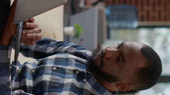 Vertical Video African American Worker Analyzing Financial Report on Laptop