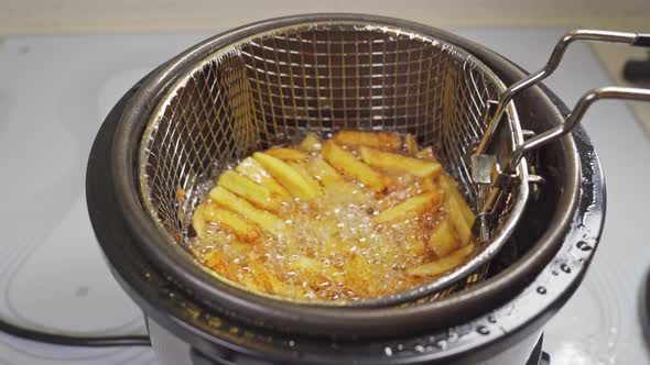 a Basket of Potatoes is Taken Out of the Deep Fryer