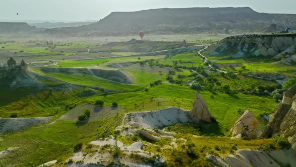 Hot air balloons fly over the mountainous landscape of Cappadocia, Turkey.