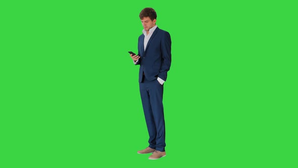 Serious Businessman Looking at His Phone on a Green Screen Chroma Key
