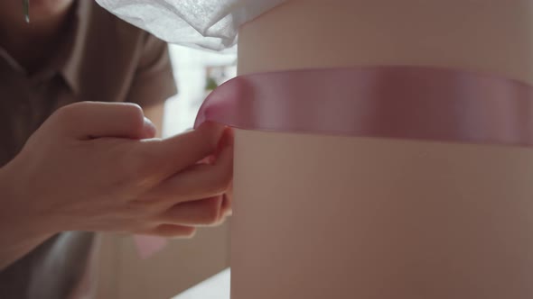 Young Woman Decorating Flower Composition in Hatbox with Ribbon on Masterclass