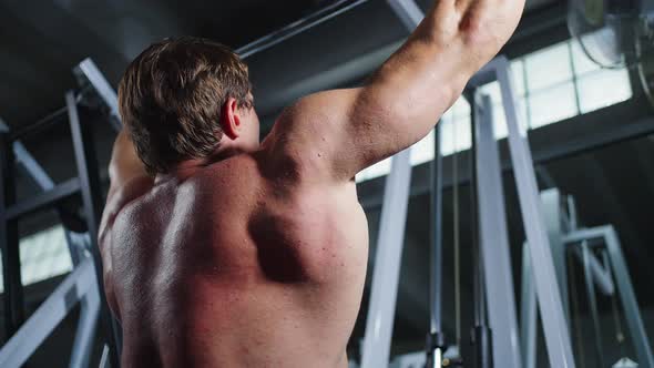 4K Caucasian man bodybuilder pulling weight lifting machine at gym.