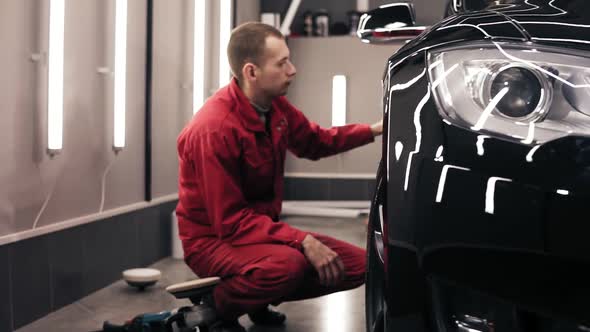 Autocenter Worker Doing the Final Wiping of Perfectly Polished New Black Car