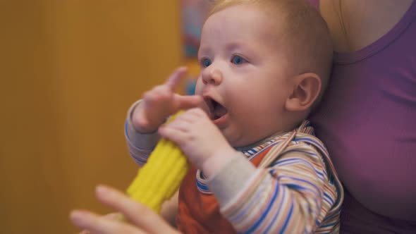 Cute Little Boy Eats Boiled Corn on Cob with Mother in Room