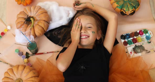 Top view of Smiling girl lying on the floor between drew pumpkin