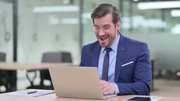 Excited Young Businessman Celebrating Success on Laptop