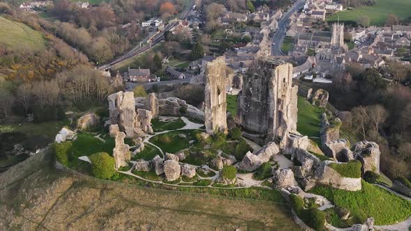 Aerial top-down orbiting around old English Corfe Castle perched on hill