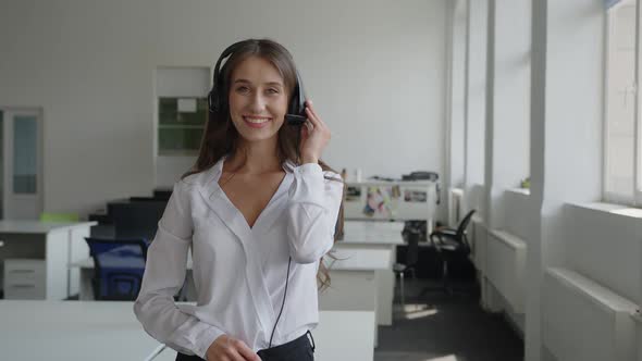 Young Woman Stands and Holds Her Black Headphones