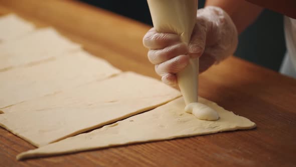 Woman making a croissant from dough in the kitchen