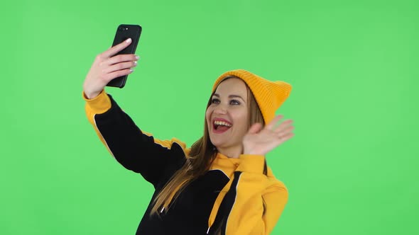 Portrait of Modern Girl in Yellow Hat Is Talking for Video Chat Using Mobile Phone. Green Screen