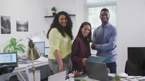 Portrait of smiling diverse group of business people looking at camera in modern office