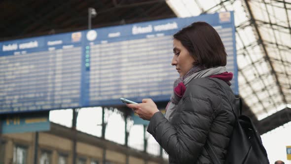 Нoung Woman is Using a Smartphone While Waiting for a Train As Arrival