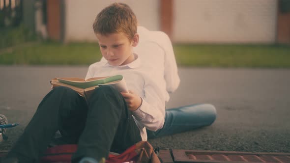 Pupil in Shirt Does Home Task Sitting on Asphalt with Friend