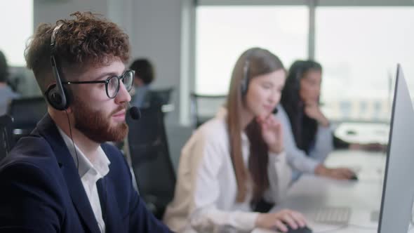 Portrait of a Technical Customer Support Specialist Talking on a Headset While Working on a Computer