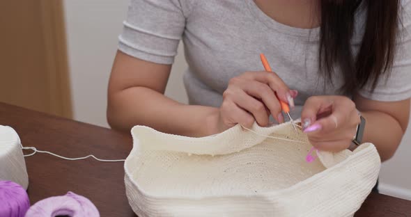 Woman knitting with crochet hook and yarn at home