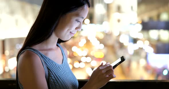 Woman using mobile phone in the city at night 