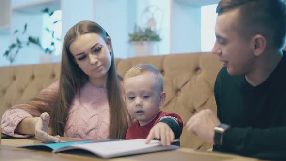 Small Child Sits Between Pretty Lady and Handsome Man