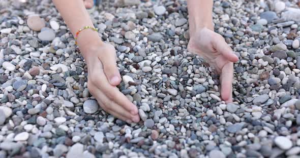 Children's Hands are Picking Up Small Sea Pebbles in Their Palms